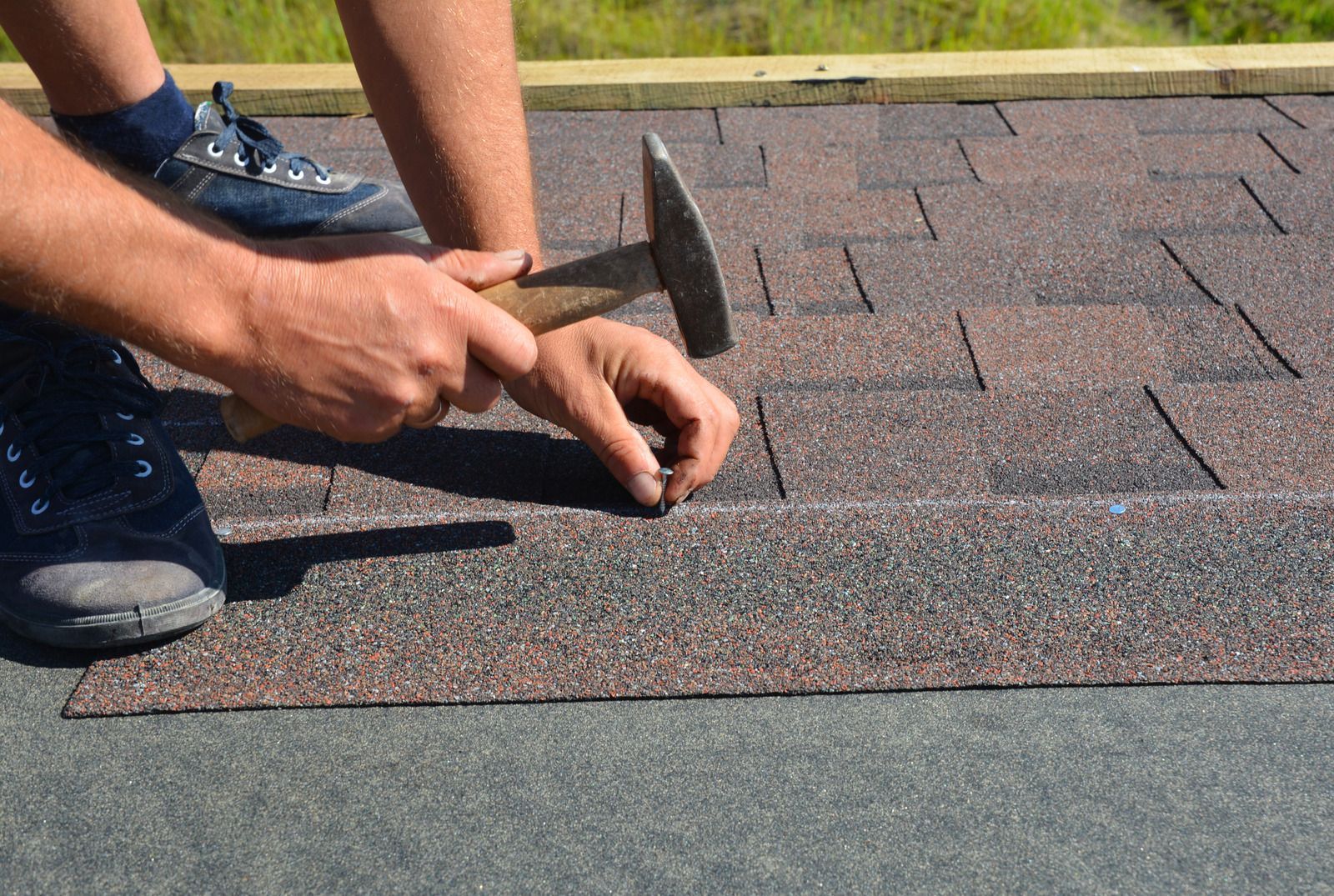 A man is hammering nails into a roof with a hammer.